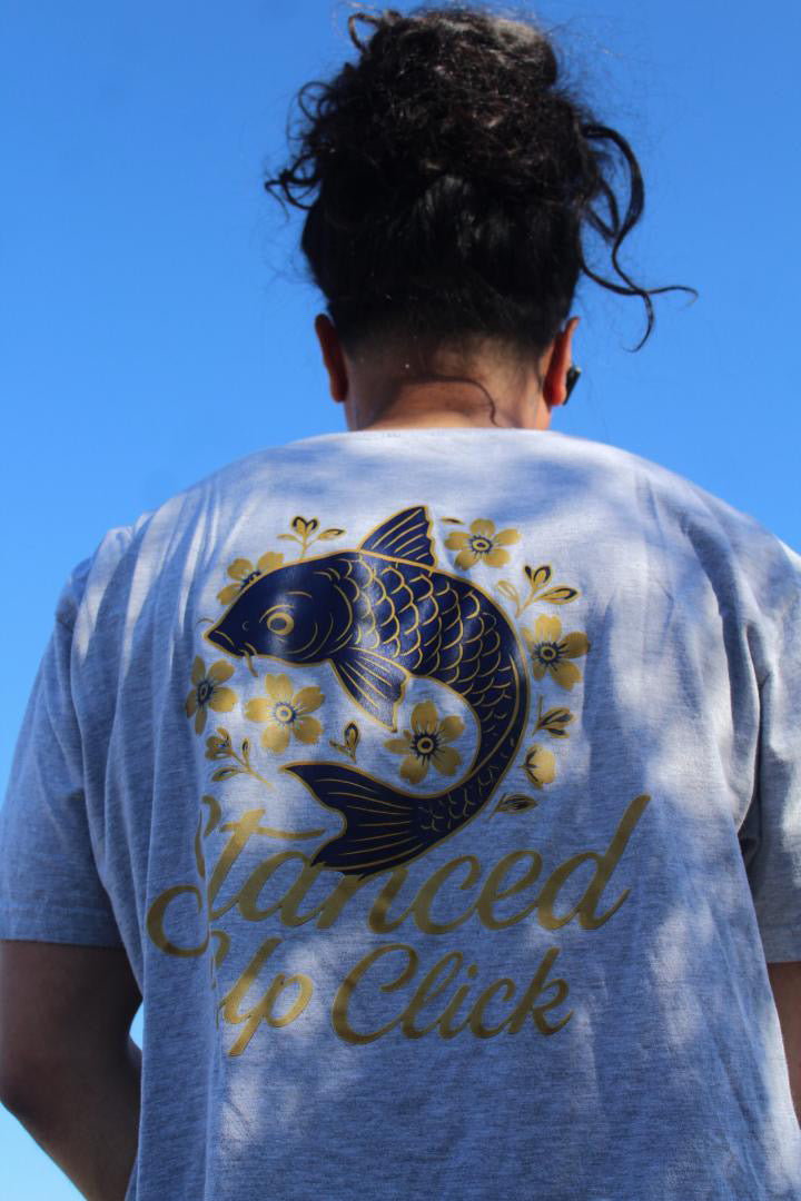 SUC Worldwide Koi Fish Tee worn outdoors, back view of the heather gray unisex tee with navy koi and gold cherry blossom print