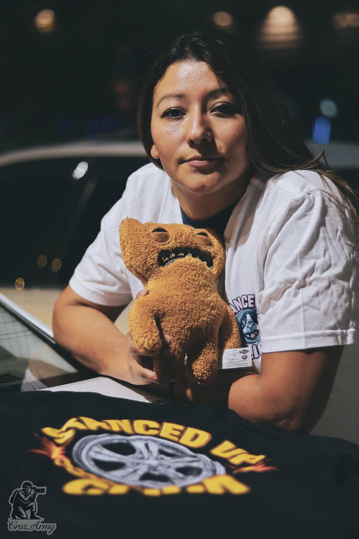 SUC Worldwide On Dubs Tee in black displayed at a car meet, chrome wheel and flame graphic with gold Stanced Up Click lettering